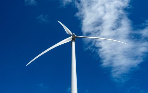 a wind turbine in front of a bright blue sky, shot from a low angle