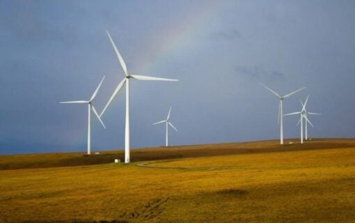 wind turbines below a rainbow